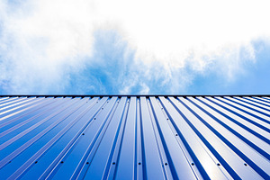 Low-angle view of a blue corrugated metal wall against a bright, a Background Photo by Ales Munt