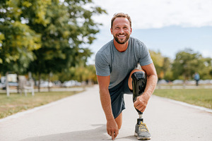 Smiling man with prosthetic leg in park, a Sports & Recreation Photo by AlyaAnd