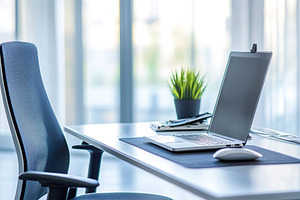 Organized modern office workspace with laptop and armchair, a Photo by AlyaAnd