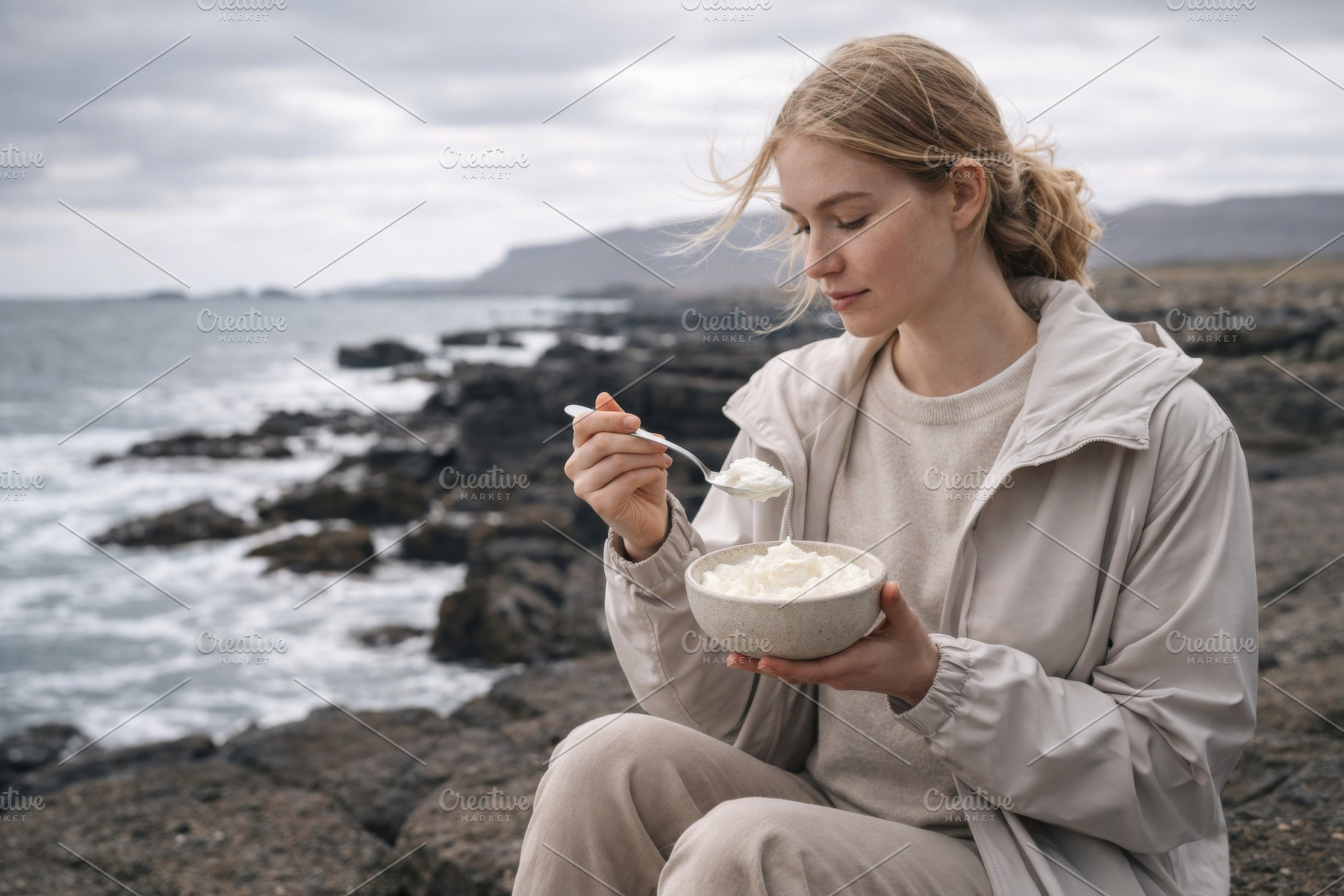 Woman eating skyr on a rocky Iceland, a Photo by Dvoevnore photos