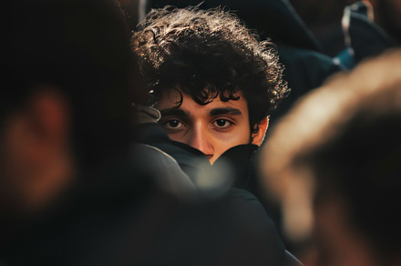 Young Man Peering Through Crowd with Curly Hair, an Abstract Photo by Natalia Klenova's Shop