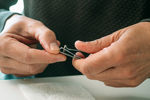 a man trims his thumb nail with precision, a Photo by Nito
