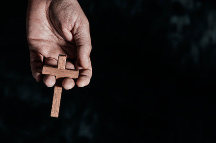 man holds a wooden cross in his hand, a Photo by Nito