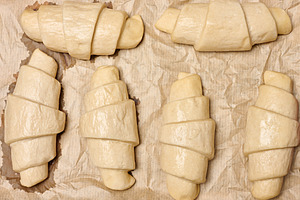 Uncooked croissant blanks on parchment paper, a Food & Drink Photo by ndanko