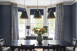 Contemporary dining room with blue walls, black table, pendant l, a Photo by Studio ANNA