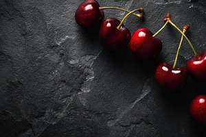 Cherries on dark stone surface, a Photo by Beautiful things
