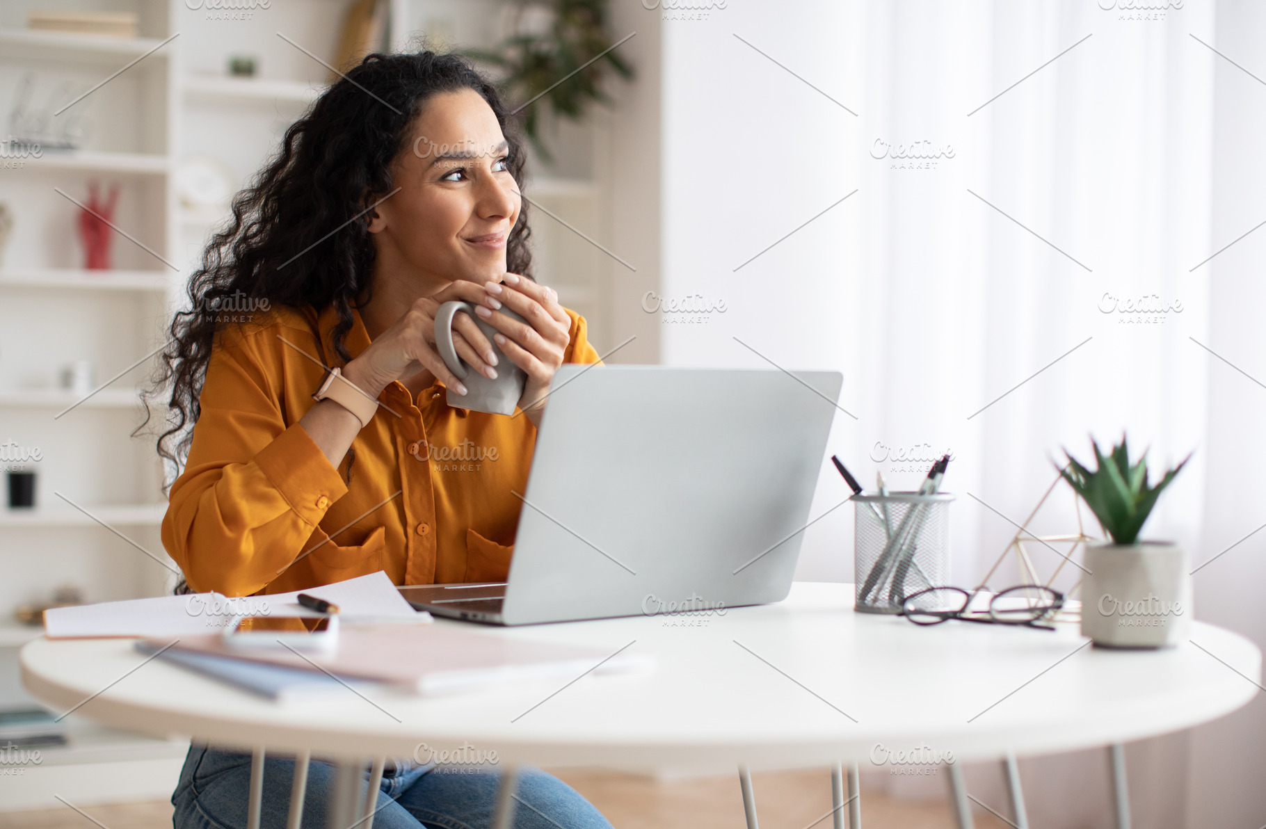Dreamy Businesswoman Using Laptop And Holding Coffee Cup Indoors, a Photo by Prostock-Studio
