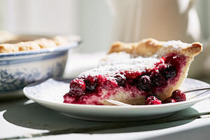 Slice of berry pie dusted with powdered sugar on a plate, offering a taste of c, a Photo by Studio ANNA