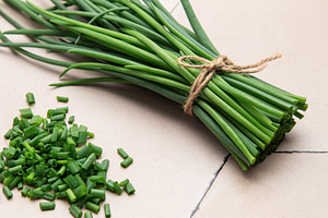 Freshly cut chives tied with twine on a tiled surface, a Food & Drink Photo by Olena Rudo