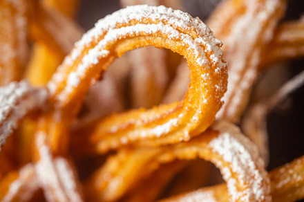 Traditional Spanish churros on the table. Dark and moody photo, close up, a Food & Drink Photo by zakiroff