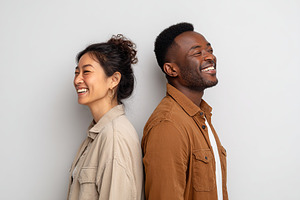 Friends sharing laughter while standing back to back in a studio setting, a Photo by AlyaAnd