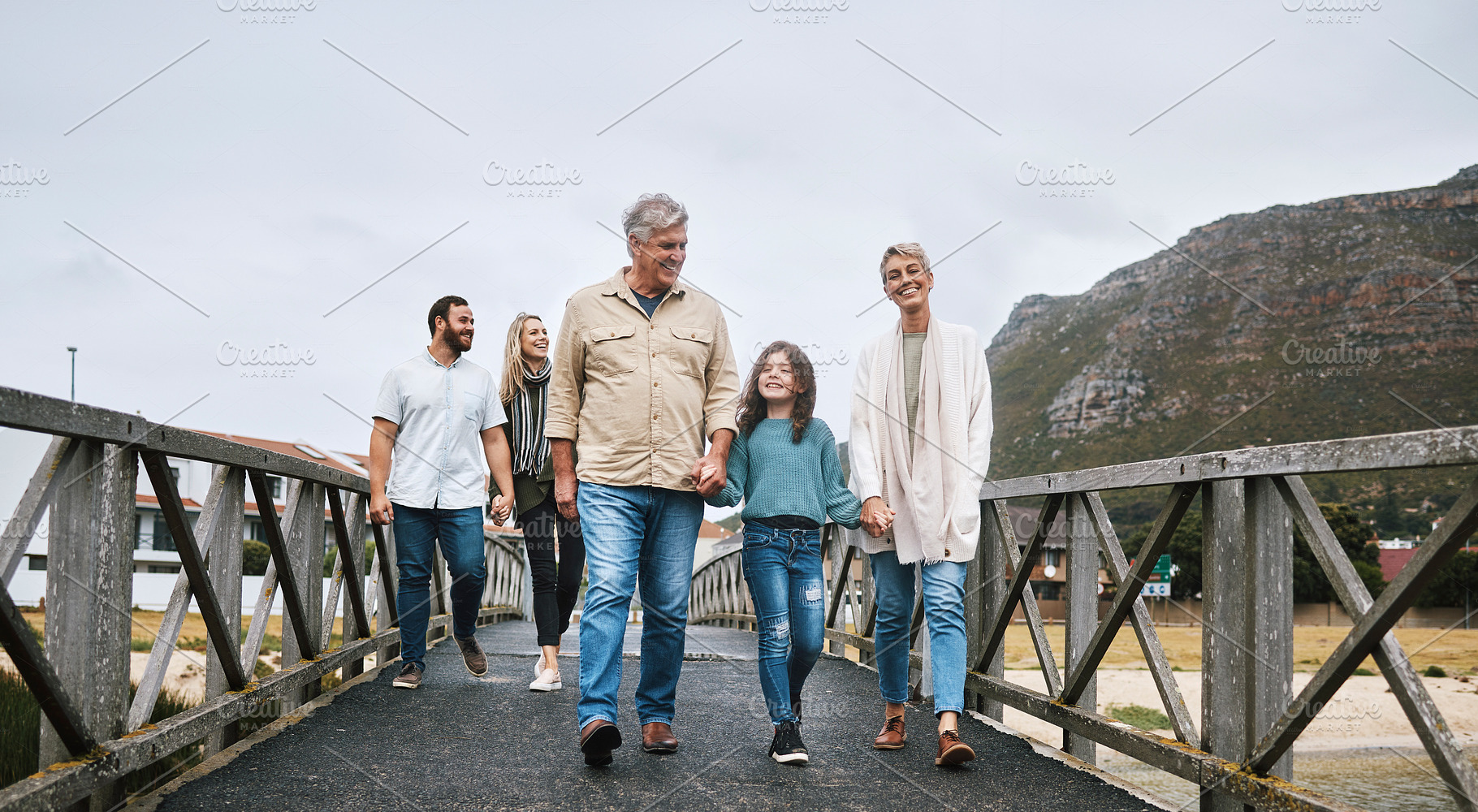 Family, walking and travel with a girl and grandparents holding hands on a pier while on holiday or vacation together. Love, trust and children with a man, woman and granddaughter boding on a walk, a Photo by Peopleimages.com