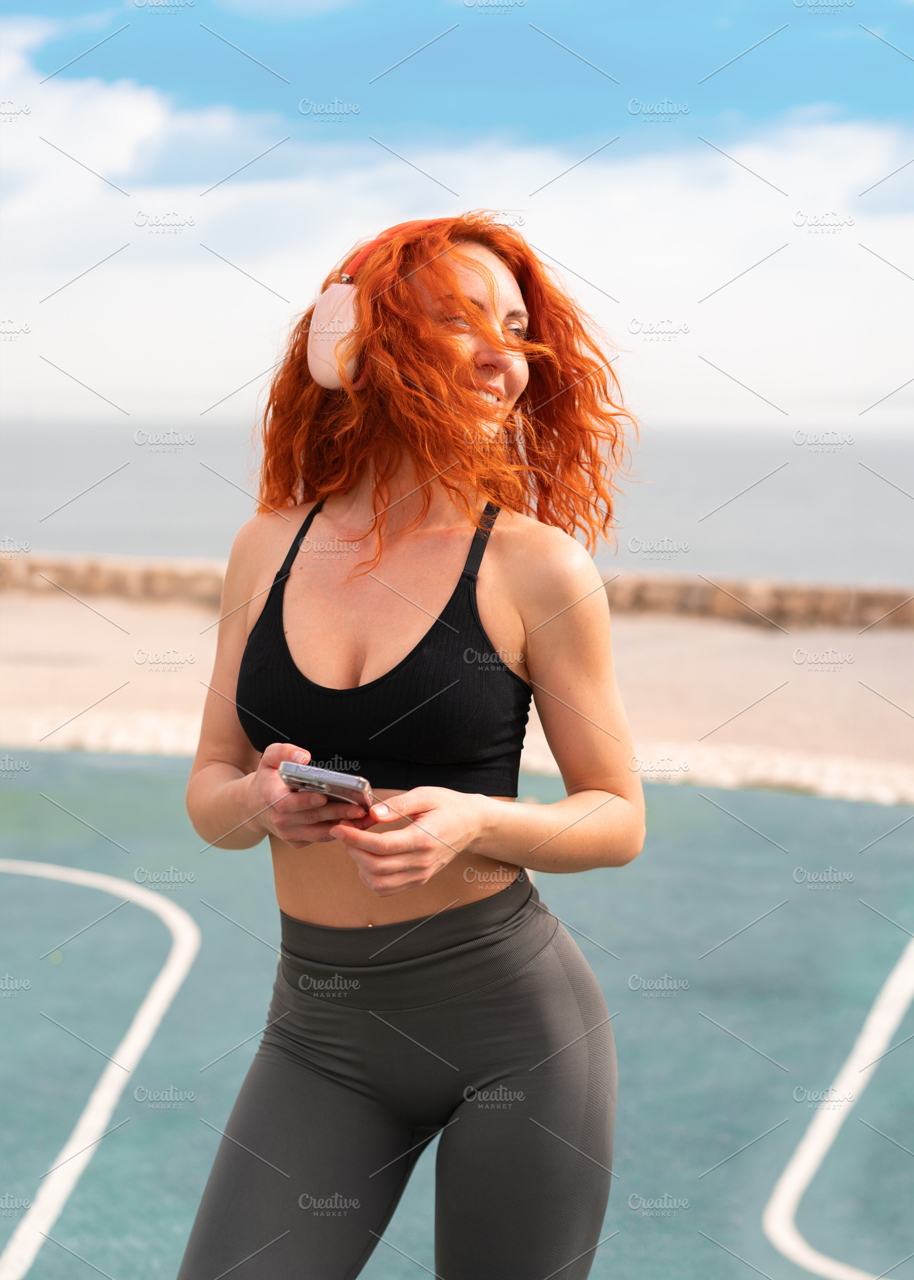 Fit woman with smartphone listening to music at outdoor gym, a Person Photo by andreonegin market