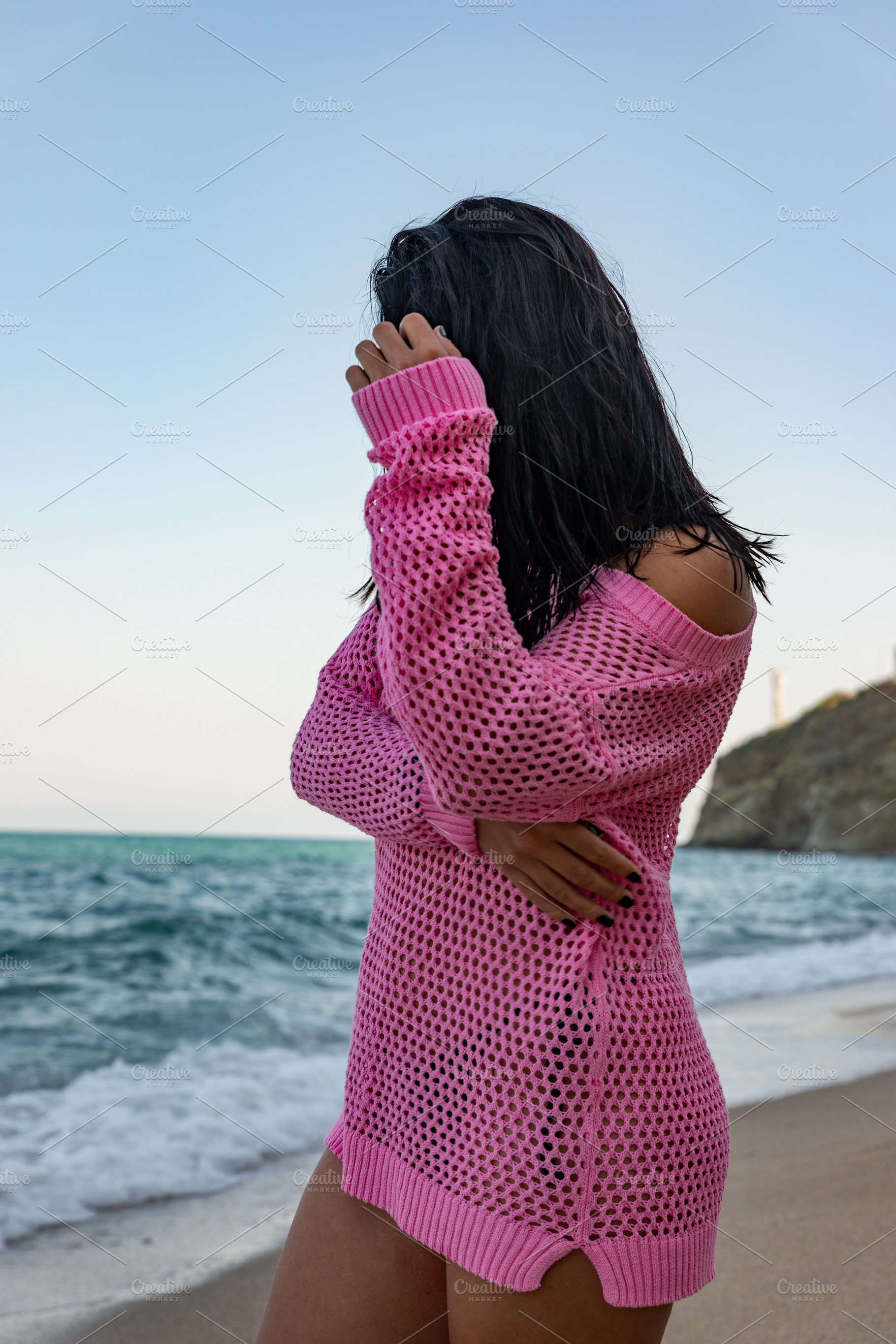 Woman in a pink mesh sweater standing on a sandy beach near the ocean, serene n, a Person Photo by Ales Munt