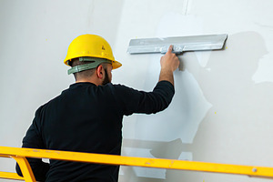 Construction worker applying plaster on a wall using a spatula, an Industrial Photo by Antonio Gravante Market