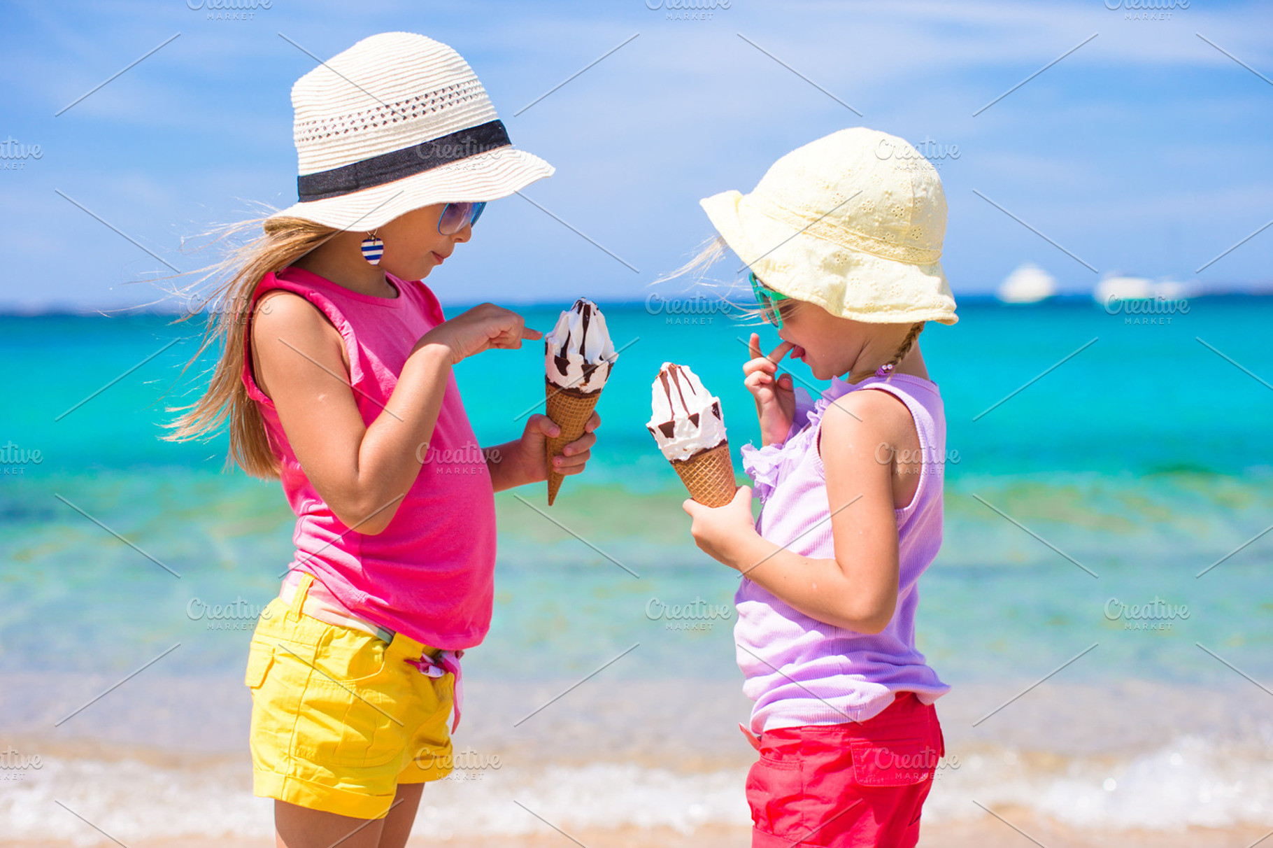 Happy little girls eating ice-cream over summer beach background. People, children, friends and friendship concept, a Person Photo by travnikovstudio
