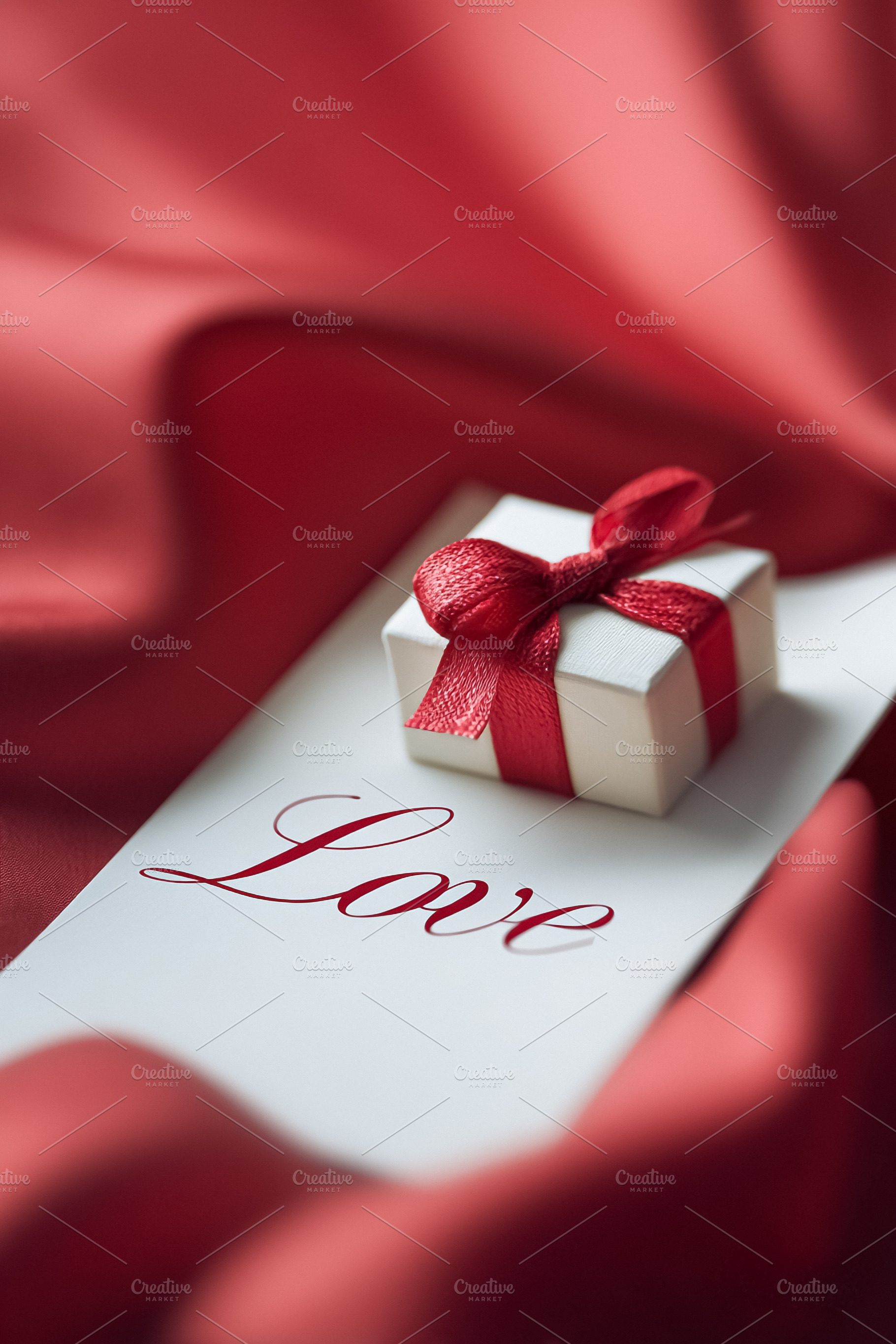 Little present with red ribbon on card with Love writing, symbol, a Photo by Studio ANNA