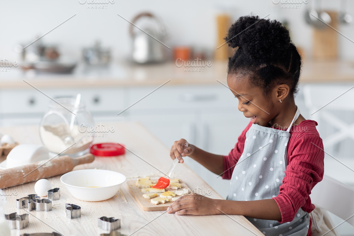 Adorable little black girl making cookies, side view, a Photo by Prostock-Studio (Photo 1 of 2)