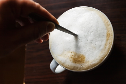 Cup of coffee with foam being stirre, a Food & Drink Photo by TanaCh