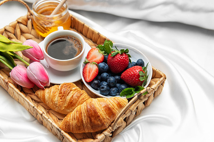 Romantic breakfast in bed with coffee, croissants, berries, hone
