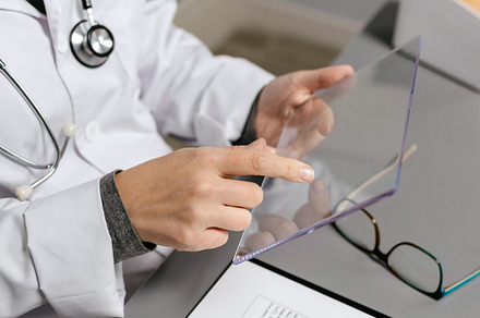 Unrecognizable female doctor touching with finger transparent tablet, a Health & Medical Photo by davidpereiras