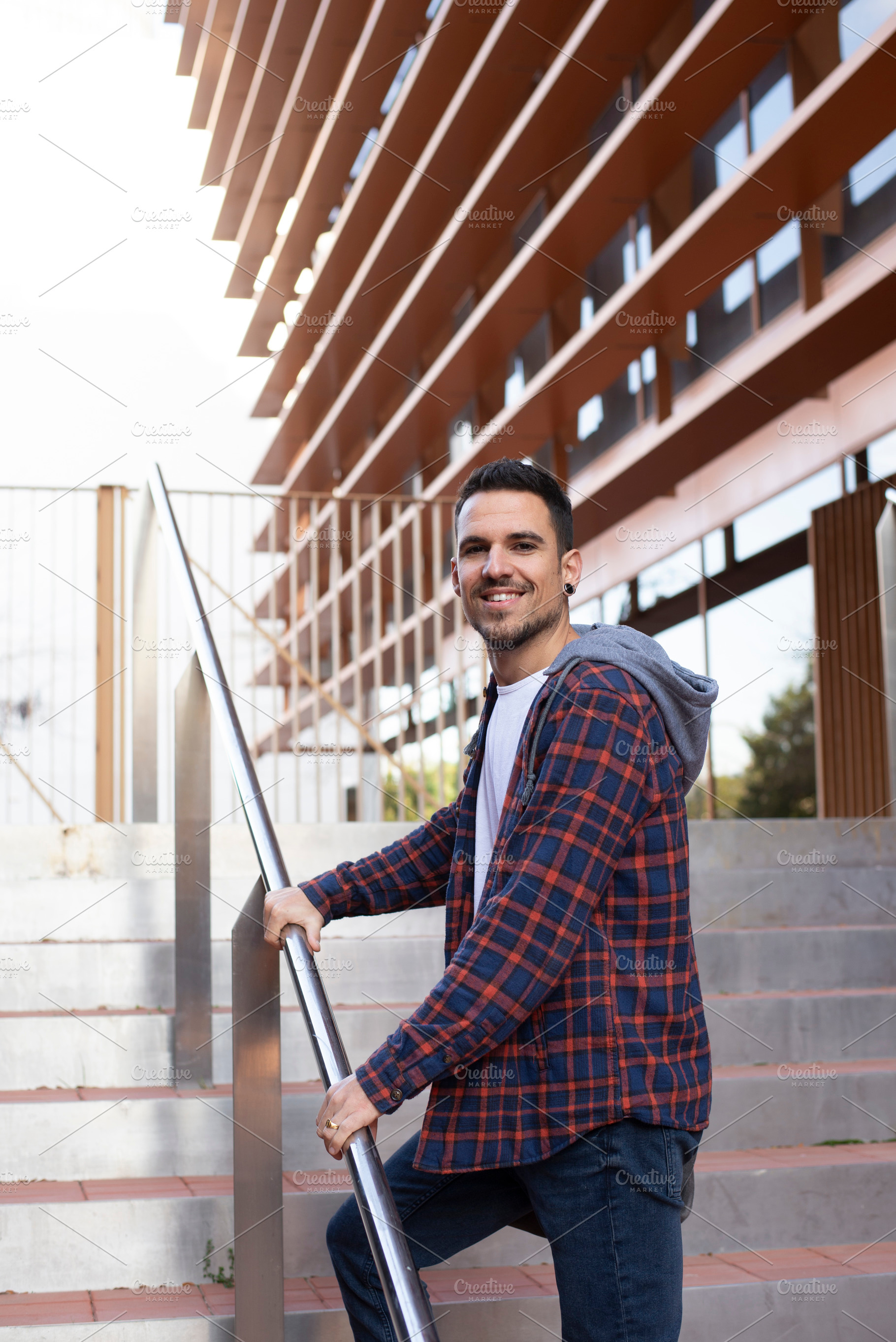 Young man smiling on outdoor stairs near modern building, a Person Photo by RF Images