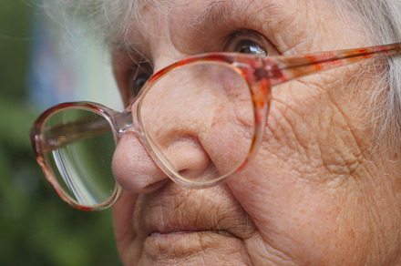 Old woman in glasses looking forward. Granny wearing eyeglasses outside. Portrait of grandmother outdoor. Close up Side view Slow motion