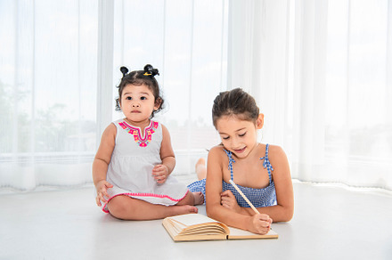 Happy two sister drawing in sketch book together at home or nurs, a Person Photo by Ministocker