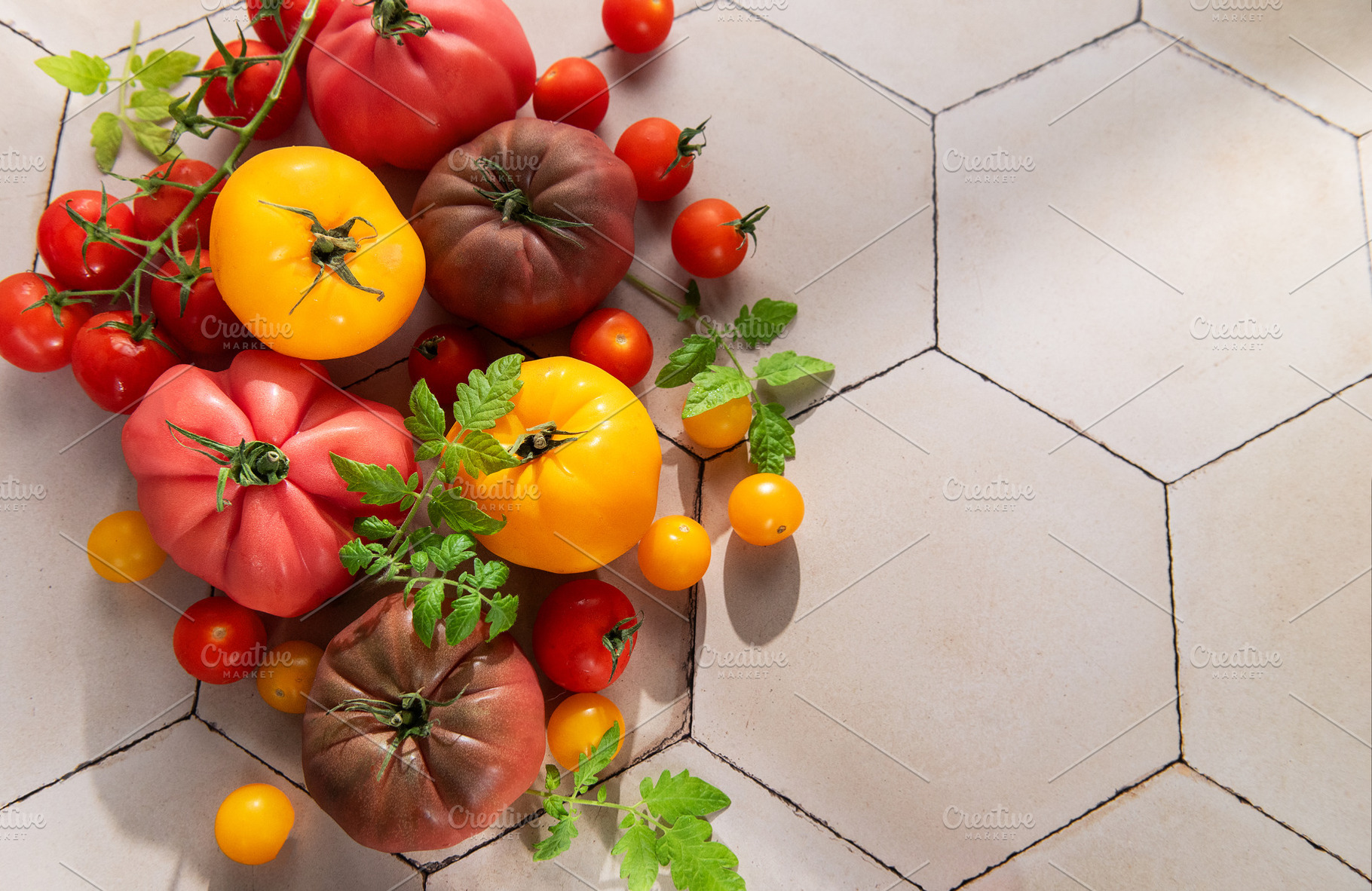 Colorful heirloom tomatoes and cherry tomatoes on tile, a Food & Drink Photo by Olena Rudo
