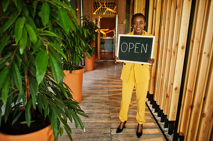 African american woman hold open welcome sign board in modern ca, a Business Photo by AS photostudio