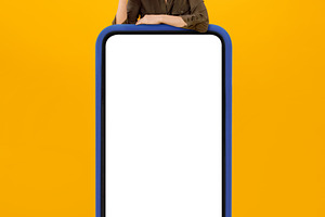 Joyful Female Tourist Posing Ner Huge Smartphone Screen, Yellow Background, a Photo by Prostock-Studio