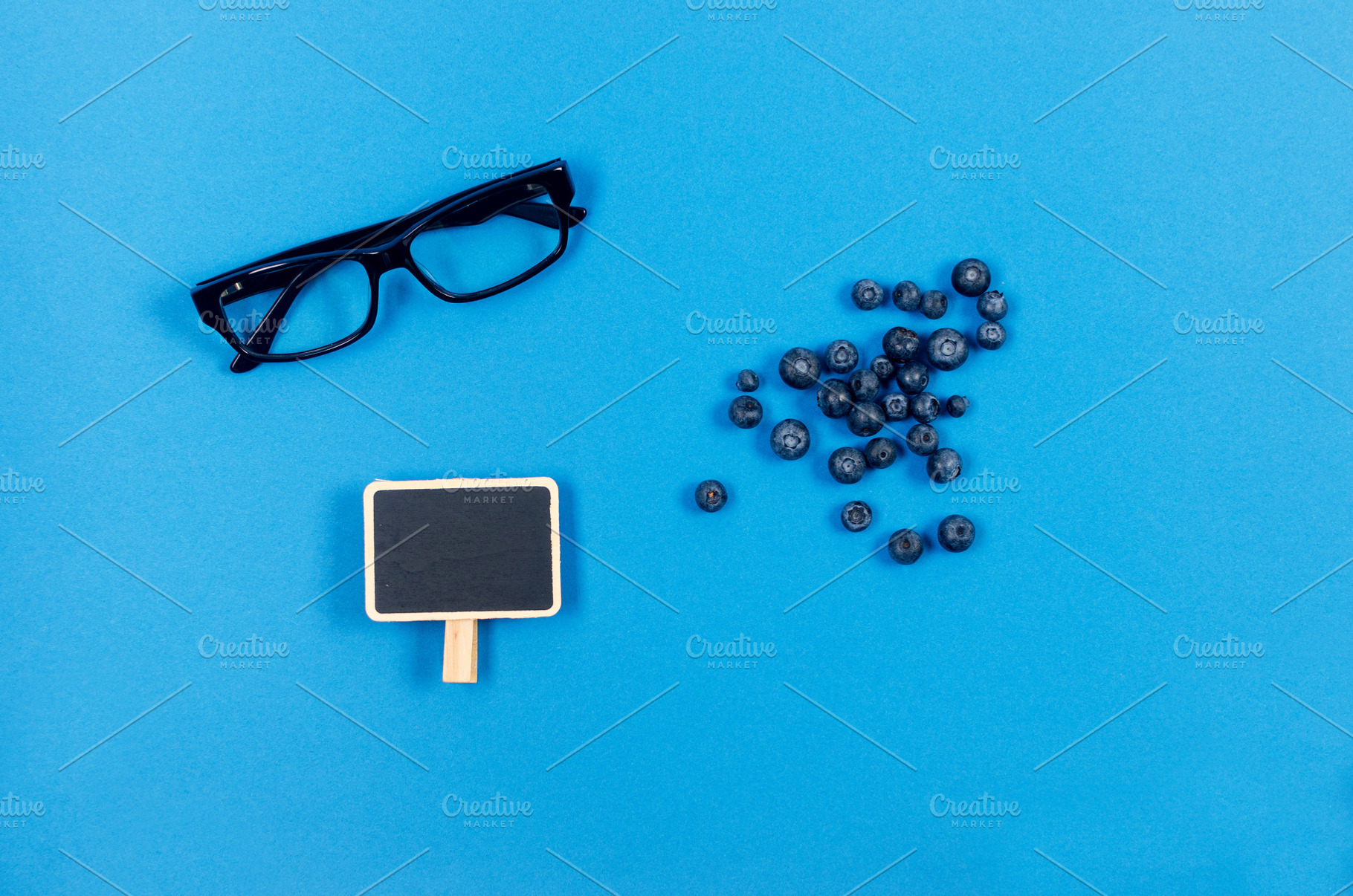 Glasses and fresh blueberries on blue background, a Photo by vimart