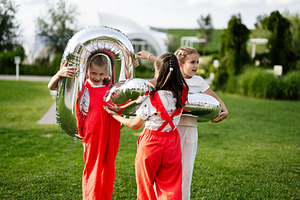 Three children playing with balloons outdoors on a sunny day in a park, a Photo by AS photostudio