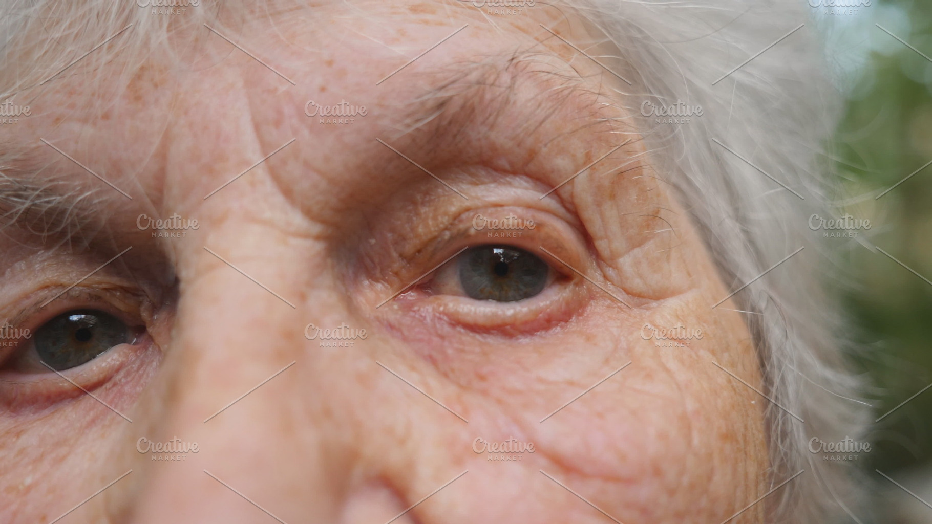 Close up portrait of old woman watching into camera and then looking up. Eyes of an elderly lady with wrinkles around them. Slow motion, a Person Photo by Footage Autor
