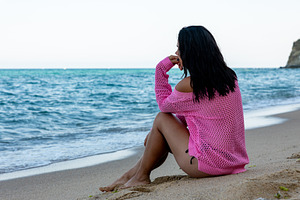 Woman in a pink sweater sitting alone on sandy beach, gazing at the ocean. Sere, a Person Photo by Ales Munt