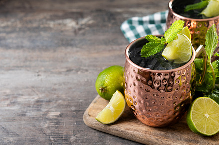Moscow mule cocktail served with ice and lime slice on wooden table, a Food & Drink Photo by etorres69