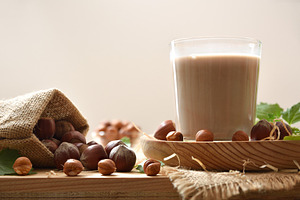 Glass of hazelnut milk on wooden plate and isolated background, a Food & Drink Photo by Davizro's Market