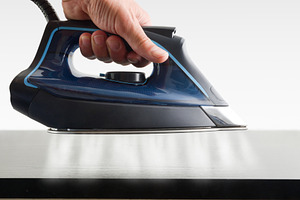 Hand operating steam iron and jets coming out on tabvle, a Technology Photo by Davizro's Market