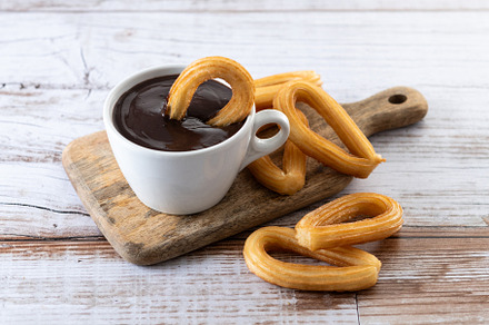 Traditional Spanish churros with hot chocolate breakfast on wooden table, a Food & Drink Photo by etorres69