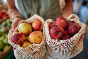Reusable produce bags filled with fresh apples and peaches at a farmers market, a Food & Drink Photo by AlyaAnd
