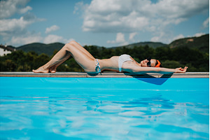 Young woman lying by the on edge of, a Person Photo by HalfPoint