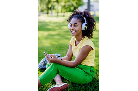 Multiracial girl sitting in grass, a Person Photo by HalfPoint