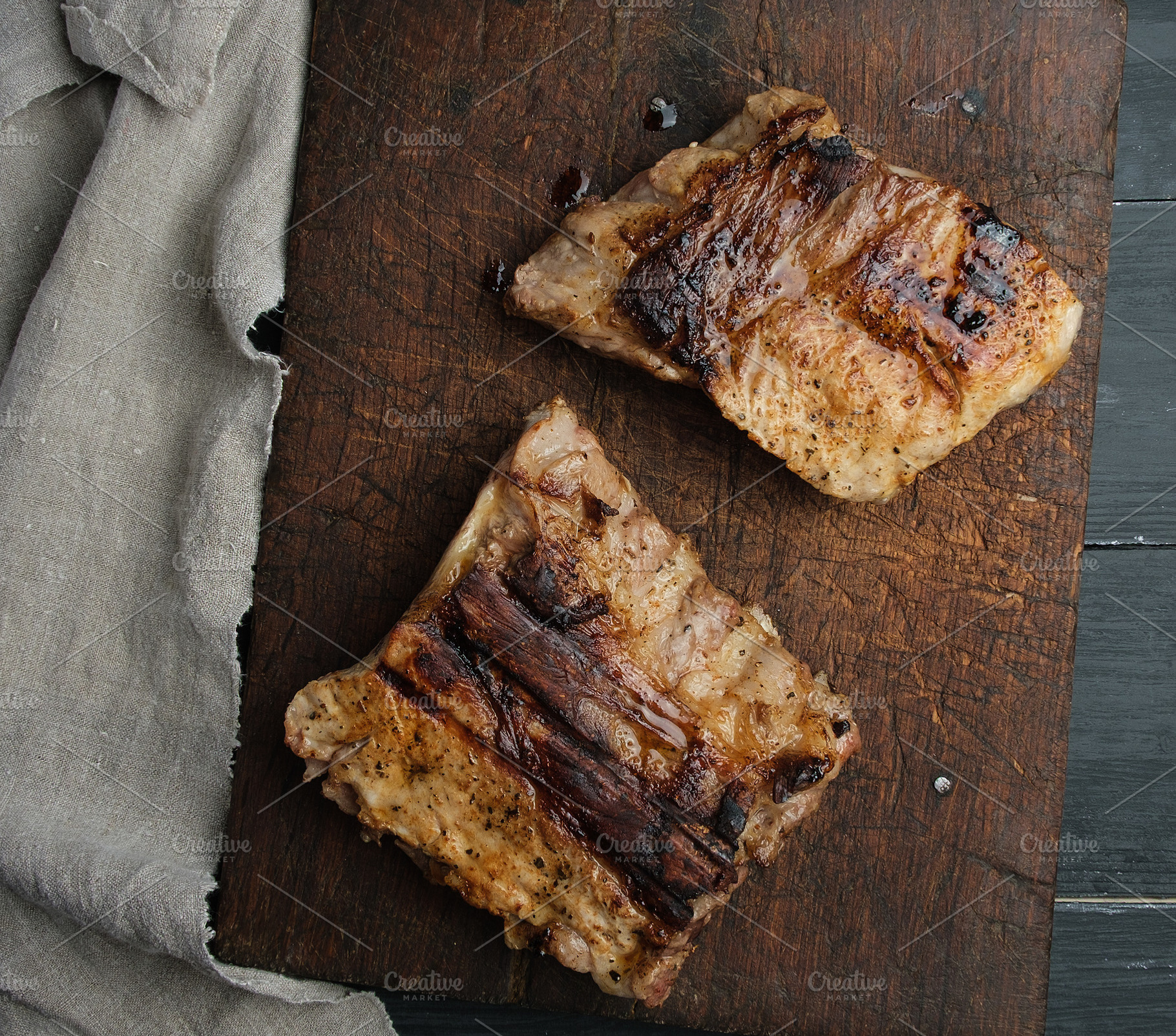 Two pieces of fried meat on an old wooden board, top view, a Food & Drink Photo by ndanko
