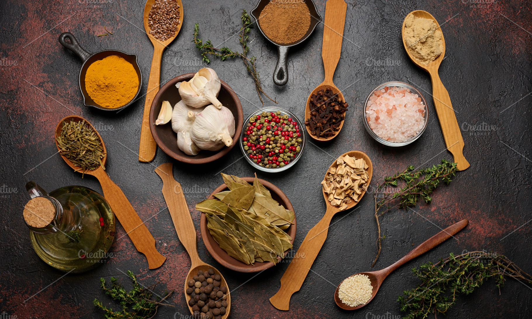 Various ground spices in wooden spoons, olive oil on dark table, a Food & Drink Photo by ndanko
