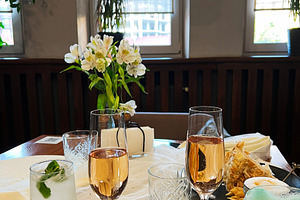 Elegant table setting with drinks, flowers, and light snacks in a cozy room, a Photo by AS photostudio