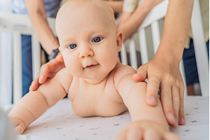 Baby lying on stomach in crib with, a Person Photo by Elizaveta Galitskaya