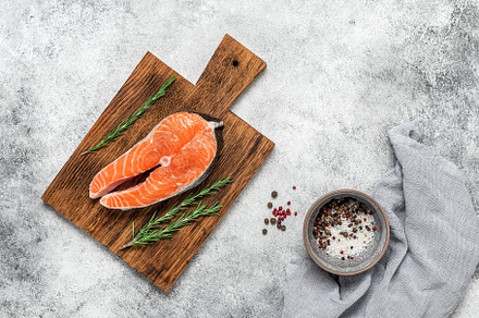 Raw salmon steak with rosemary and spices on a wooden board, gray grunge backgr, a Food & Drink Photo by Yulia71