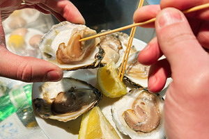 Fresh oysters served with lemon slices at a seafood market food stall, a Photo by AS photostudio