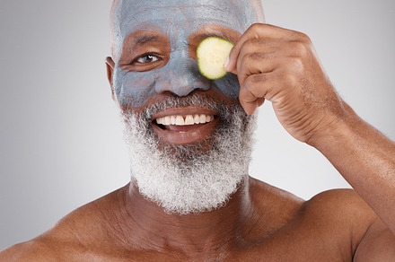 Face mask, cucumber and black man with smile in portrait, beauty and skincare isolated on studio background. Happy senior male, cosmetics and healthy skin, anti aging cosmetic routine with facial, a Photo by Peopleimages.com