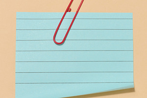 Blue sticky note with a red paper clip attached to it, placed on, a Business Photo by ndanko